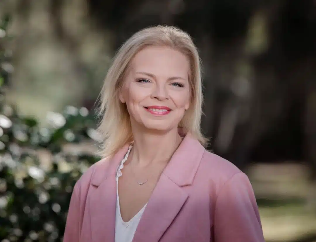 A blonde woman, VP of Operations at Four Points RV Resorts, in a pink blazer and white shirt.