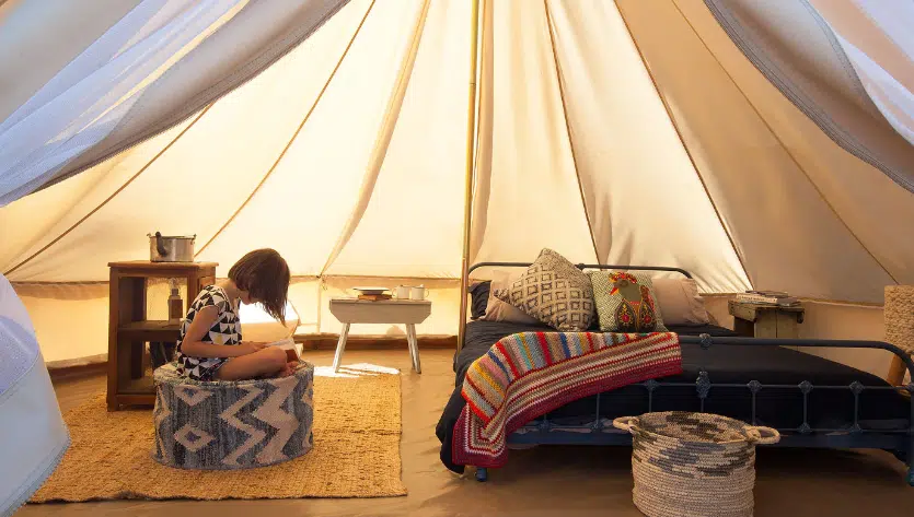 A person relaxing inside a well-appointed luxury glamping tent in South Australia with comfortable furnishings.