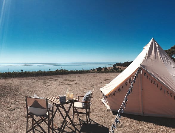 Glamping Getaways setup with a canvas tent and chairs overlooking a calm sea under a clear blue sky in South Australia.