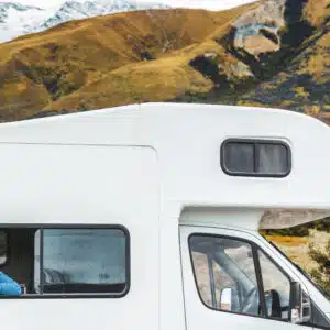 Woman looking out from the window of her RV with scenic mountainous landscape in the background, reflecting the latest trends in RV industry.