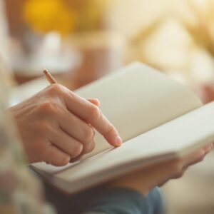A person turning the pages of a hardcover notebook in a warmly lit room.