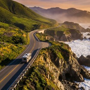 A large RV drives along a winding stretch of the Pacific Coast Highway in Big Sur, California, flanked by steep green mountains and rocky cliffs dropping into the ocean during a golden sunset