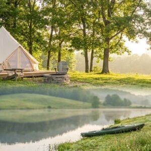 Collage showing a glamping campsite with a beige bell tent and stone fire pit in a sunny forest clearing above a serene misty lake with a green kayak resting on the grassy bank