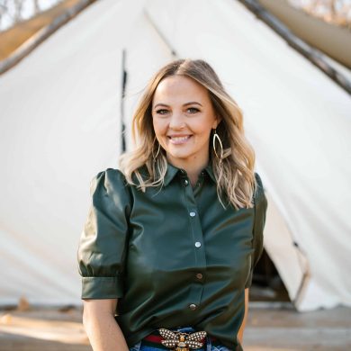 A woman in a green shirt standing in front of a MC Fireside tent.